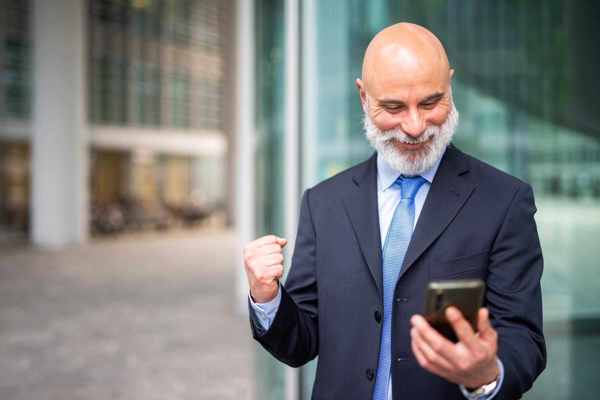 Very happy businessman looking at his phone